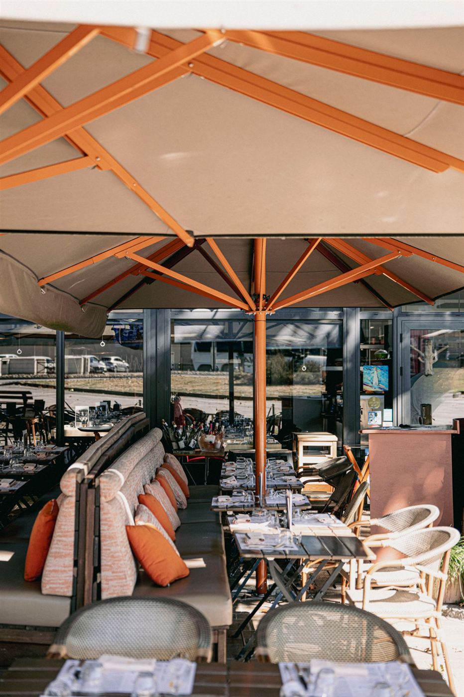 La terrasse sous les parasols, banquettes et coussins orange